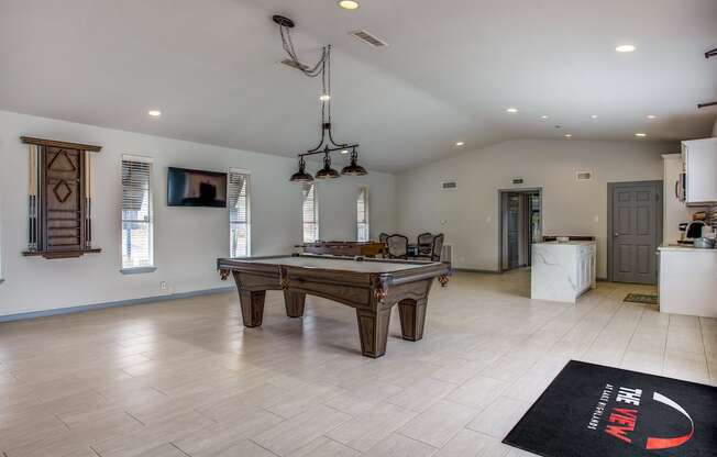 a large living room with a pool table and a kitchen