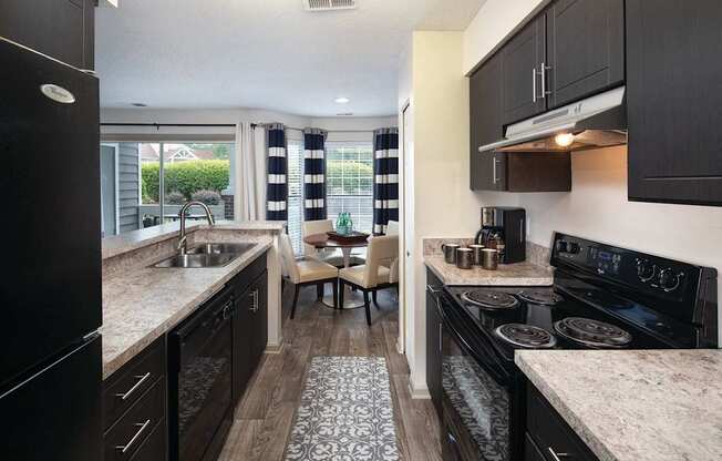 A kitchen with black cabinets and a granite countertop.