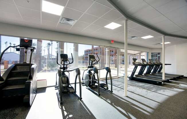 a gym with cardio equipment and a large window at Presidio Palms Apartments, Tucson, 85701