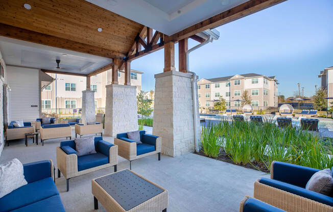 a patio with blue couches and chairs and a pool in the background at 55 Fifty at Northwest Crossing, Houston, TX