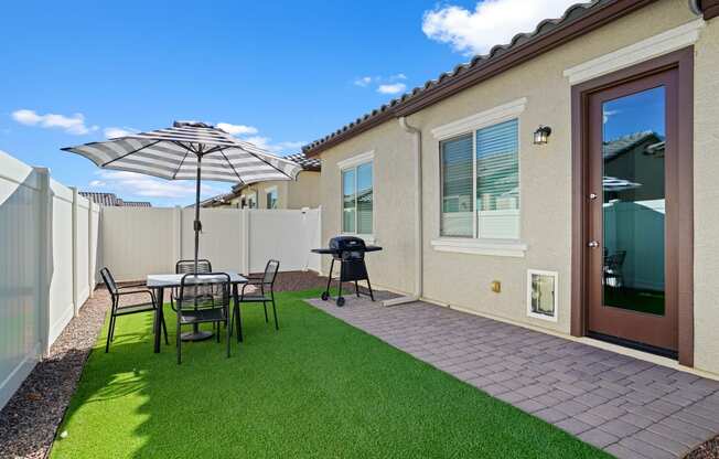 a backyard patio with a table and chairs and an umbrella