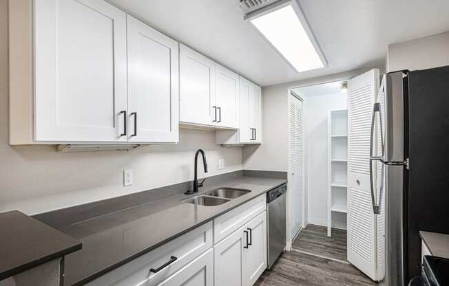 a kitchen with white cabinets and a sink and a refrigerator