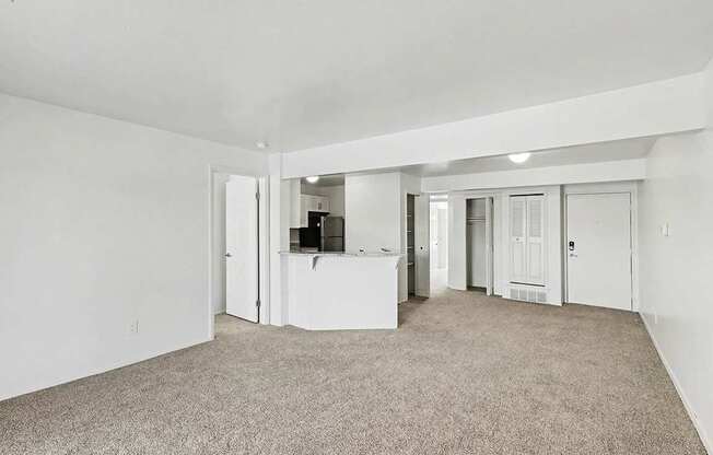 A spacious living room with carpeting and a breakfast bar at Trappers Cove Apartments, Lansing