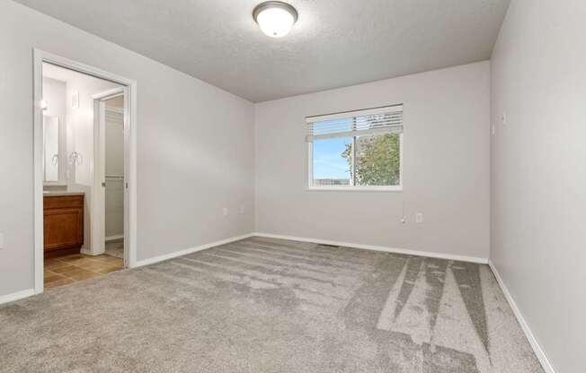 A spacious room with a carpeted floor and a window.