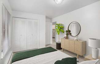 A bedroom with a bed, dresser, large closet and mirror at Brookside Apartments, Springfield