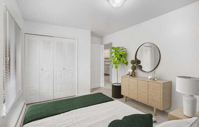 A bedroom with a bed, dresser, large closet and mirror at Brookside Apartments, Springfield