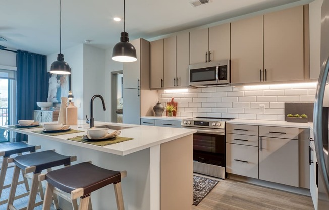 a kitchen with a large island and stools in front of a counter top at Aura Stonebridge, Richmond