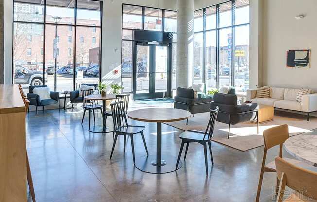 A large room with tables and chairs and a view of the street outside.