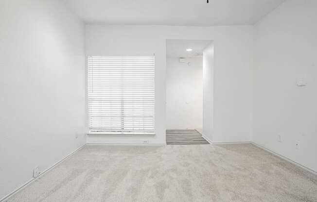 an empty room with a window and white walls