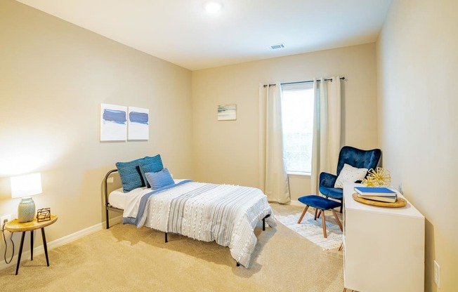 Apartment bedroom with a bed, chair and a window at Trillium apartments in Melbourne fl