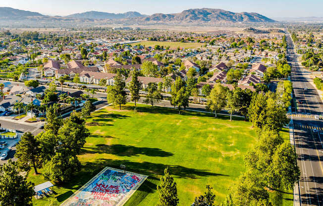 A large grassy area with a pool in the middle of a residential area.