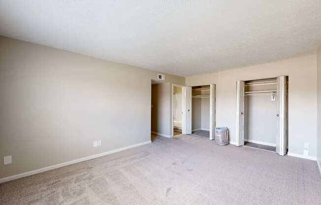 a spacious living room with a carpeted floor and a door to a hallway