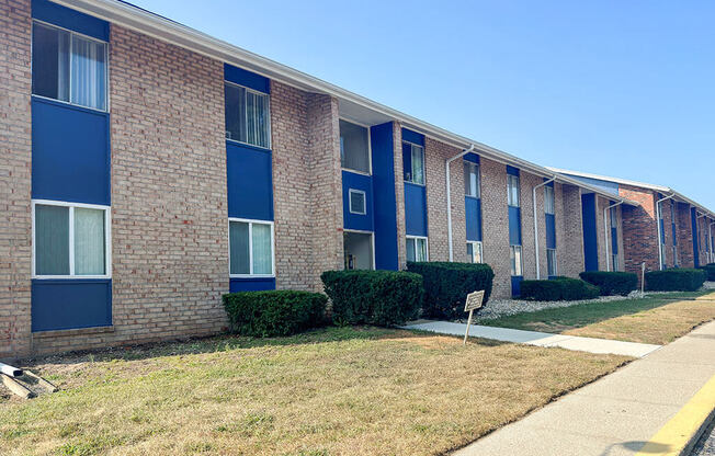 a brick building with blue windows and a sidewalk