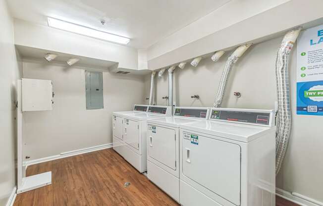 a laundry room with four washers and dryers and a row of washing machines at Sanger Place, Lorton, 22079