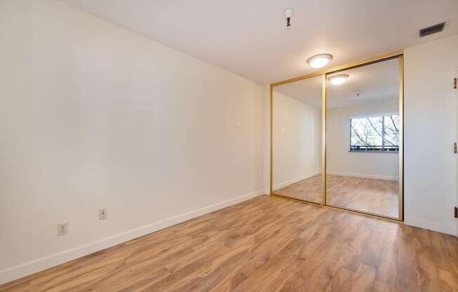 a living room with a mirror and a hard wood floor