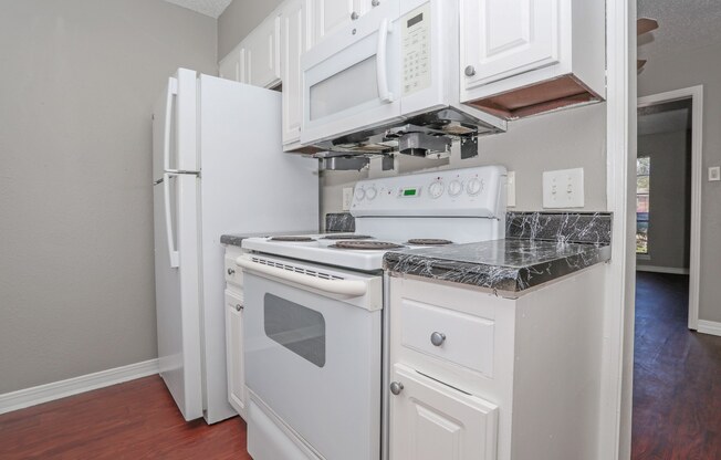 A kitchen with a white stovetop oven and microwave built into the cabinetry at Magnolia Apartments in Shreveport, LA