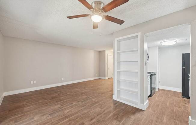 A room with a ceiling fan and wooden flooring.