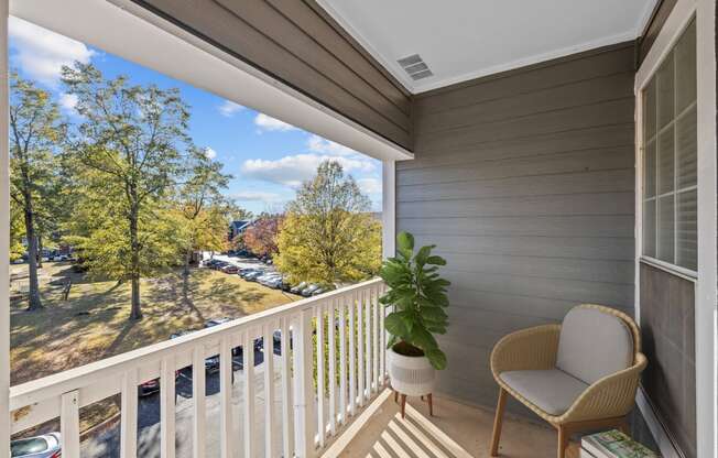 a balcony with a chair and a potted plant and a view of a park