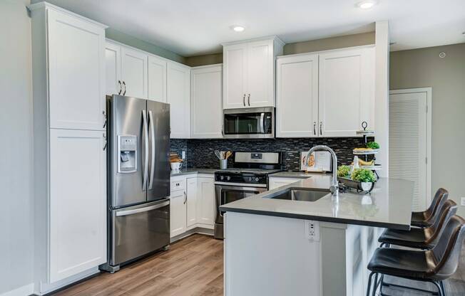 Premium kitchen featuring dark quartz countertops and white cabinetry in a two bedroom penthouse Princeton floor plan