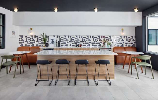 A modern bar area with a white counter and black stools.