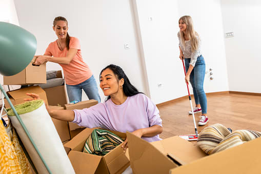 Three women are unpacking boxes in a room.