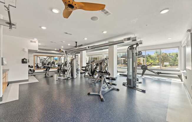 A spacious gym with a variety of equipment and a ceiling fan.