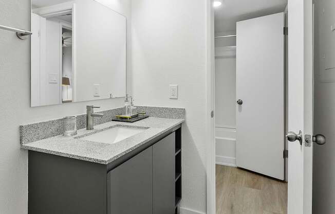 A bathroom with a sink, mirror, and cabinet.