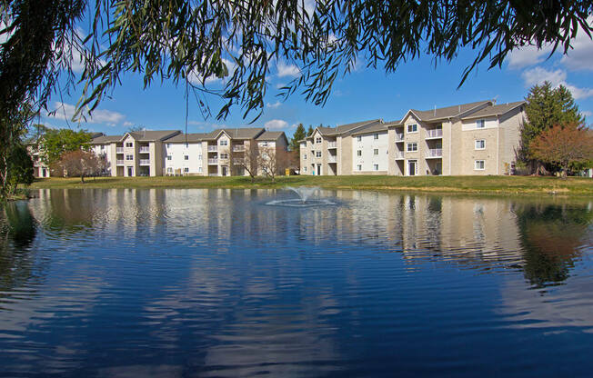 a fountain in the middle of a lake in front of an apartment building at Evergreen Luxury Apartments, Merrillville, 46410