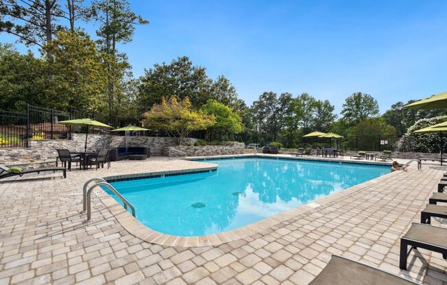 a resort style swimming pool with lounge chairs and umbrellas