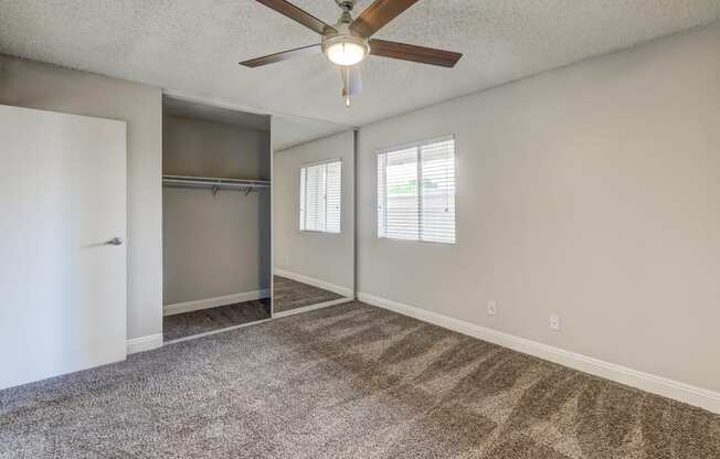 an empty living room with a ceiling fan and a closet