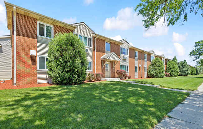 a row of brick apartment buildings with green grass and trees