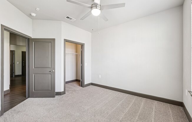 A room with a ceiling fan and a rug on the floor.