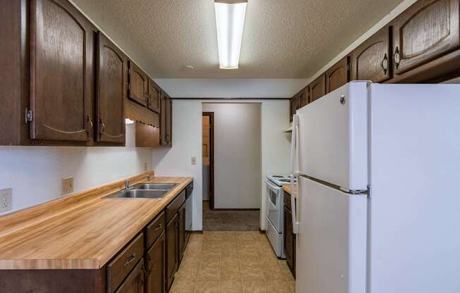 an empty kitchen with a refrigerator and a sink. Fargo, ND Plumtree Apartments