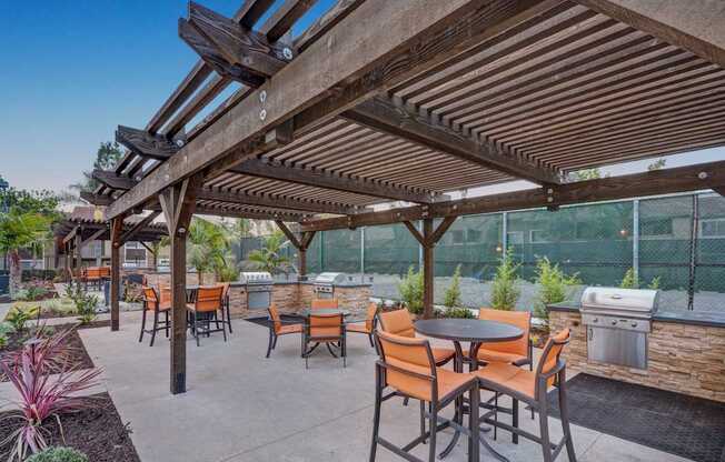A patio with tables and chairs under a wooden pergola.