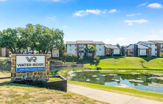 A sign for Water Ridge sits in front of a pond and houses.