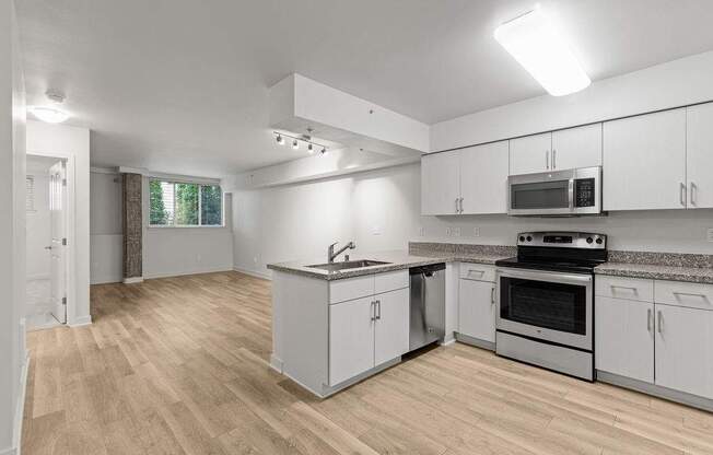A kitchen with white cabinets and a wooden floor.