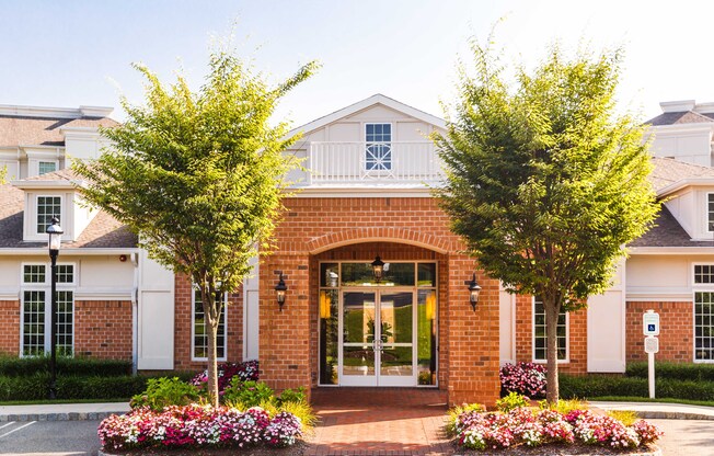 the front of a building with trees and flowers in front of it