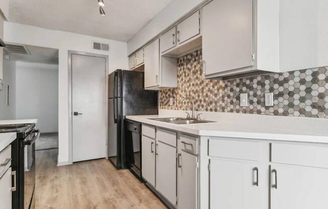 a kitchen with white cabinets and a black refrigerator