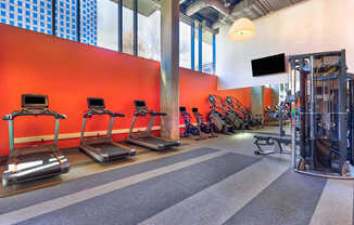 A gym with treadmills, weights and a television.