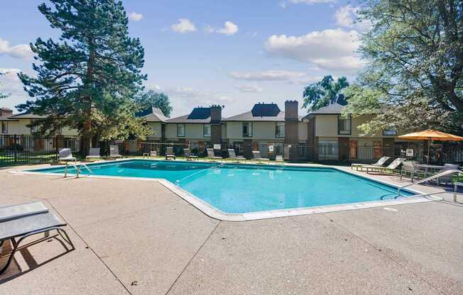 A swimming pool surrounded by a concrete patio and trees.