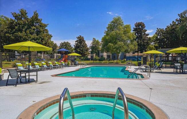 A pool with a hot tub and sun loungers.