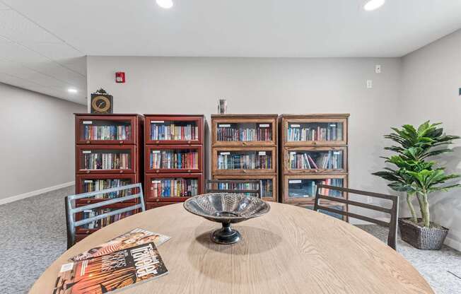 A room with a round table, a bookshelf, and a plant.