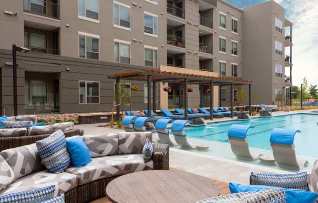 an outdoor pool with lounge chairs and tables at the bradley braddock road station apartments