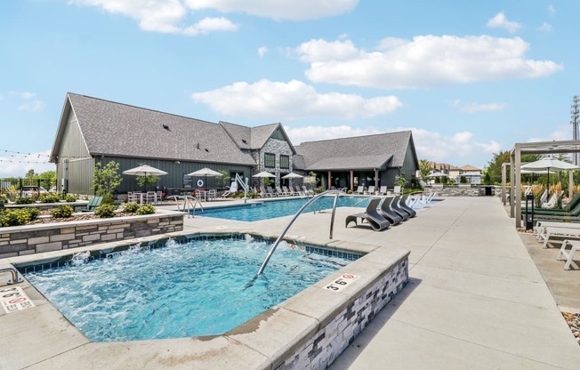 a swimming pool with chairs and a building in the background at The Depot in The Depot Raymore, MO 64083