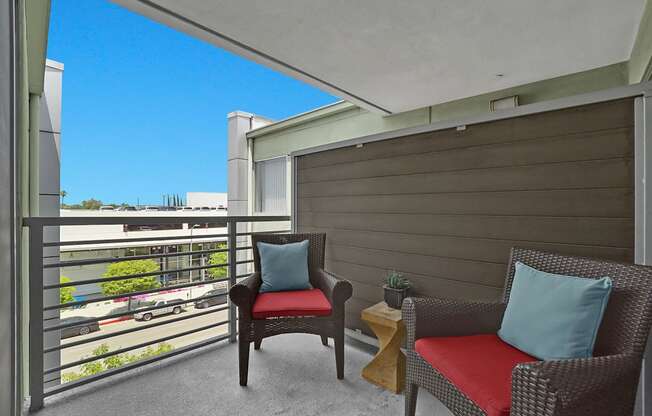 A balcony with two chairs and a small table.