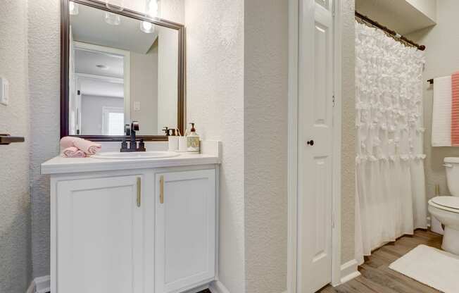a bathroom with white cabinets and a white shower curtain