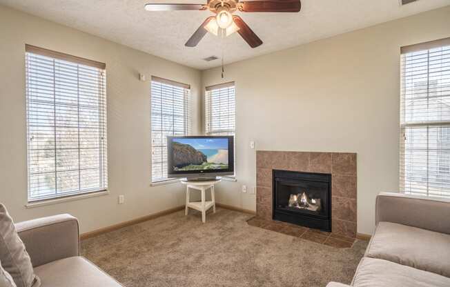 Living room with view of fireplace, ceiling fan and large windows