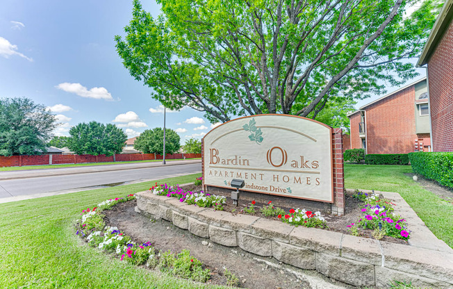 A sign for Bardin Oaks Apartment Homes sits in front of a tree.
