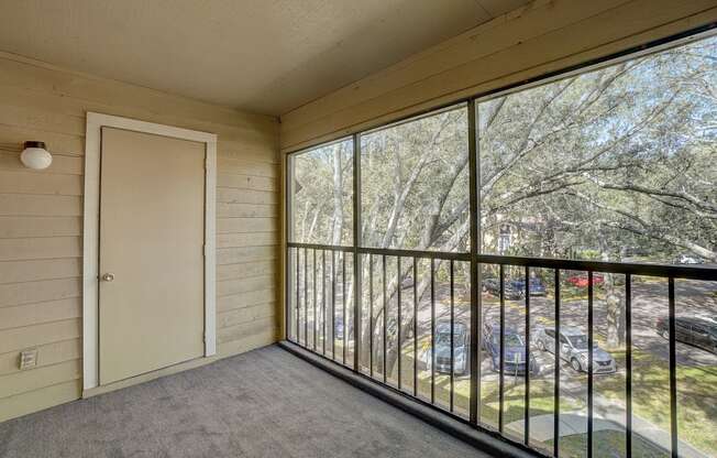 the screened in balcony has a view of the yard and the trees