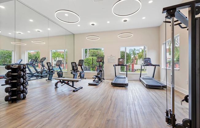 a gym with cardio machines and weights on a wooden floor